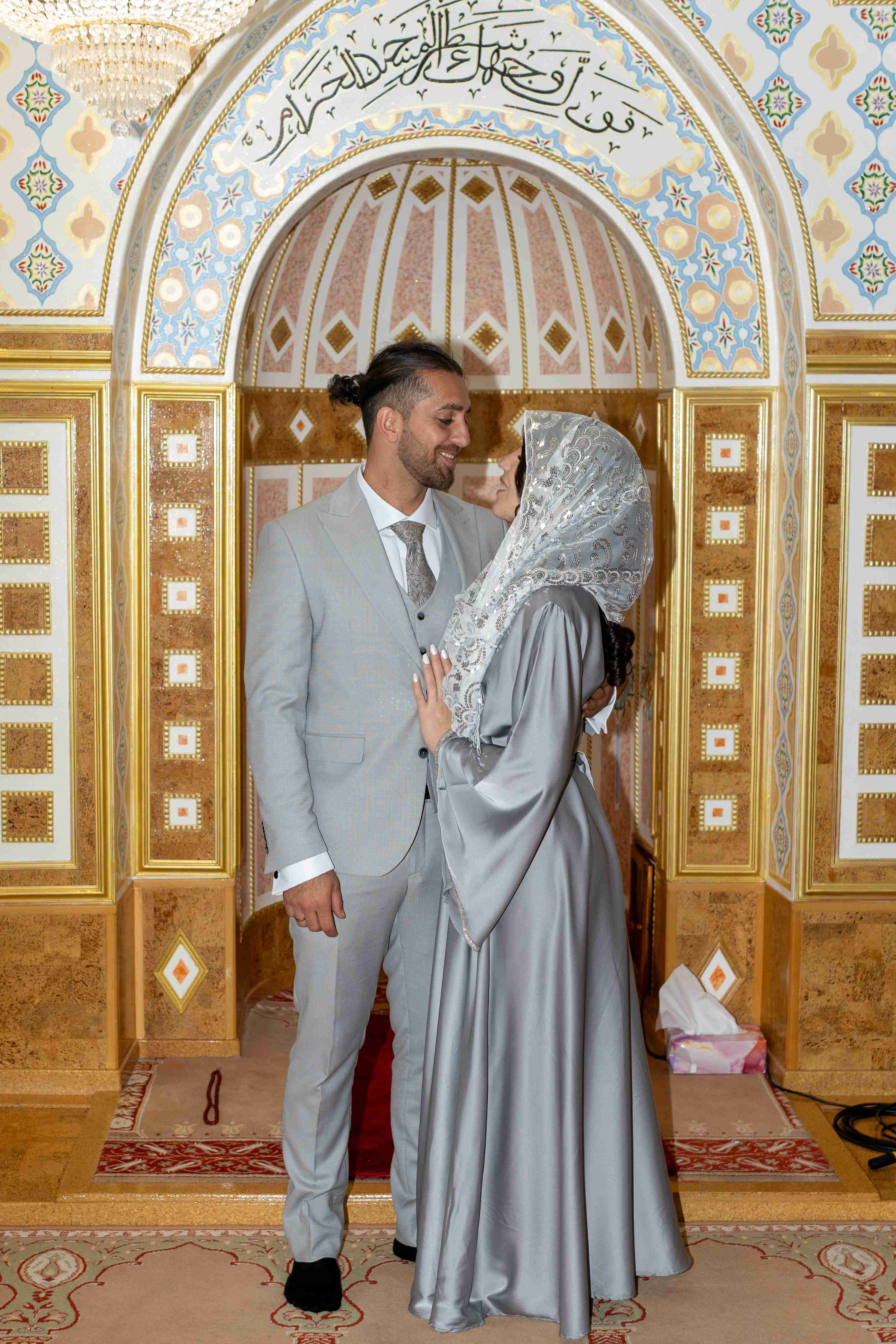 Muslimische Hochzeit in der Moschee – Brautpaar in traditionellen Outfits vor kunstvoller Architektur. Hochzeitsfotografie mit Liebe zum Detail und authentischen Emotionen.