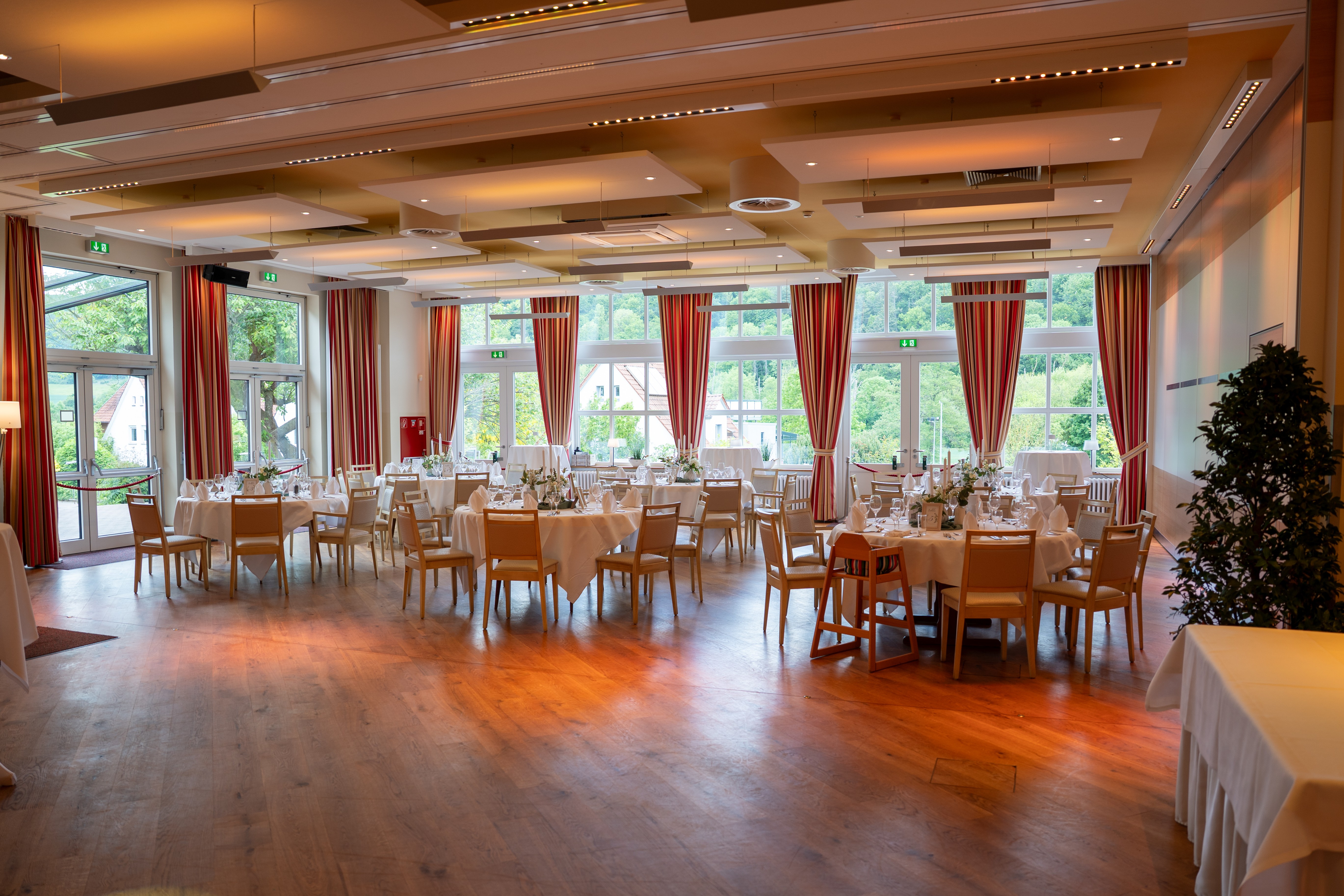 Hochzeitslocation in Mittendorf: stilvoll gedeckter Festsaal mit großen Fenstern und Ausblick ins Grüne – fotografiert von René Laeger, Hochzeitsfotograf aus Hameln.