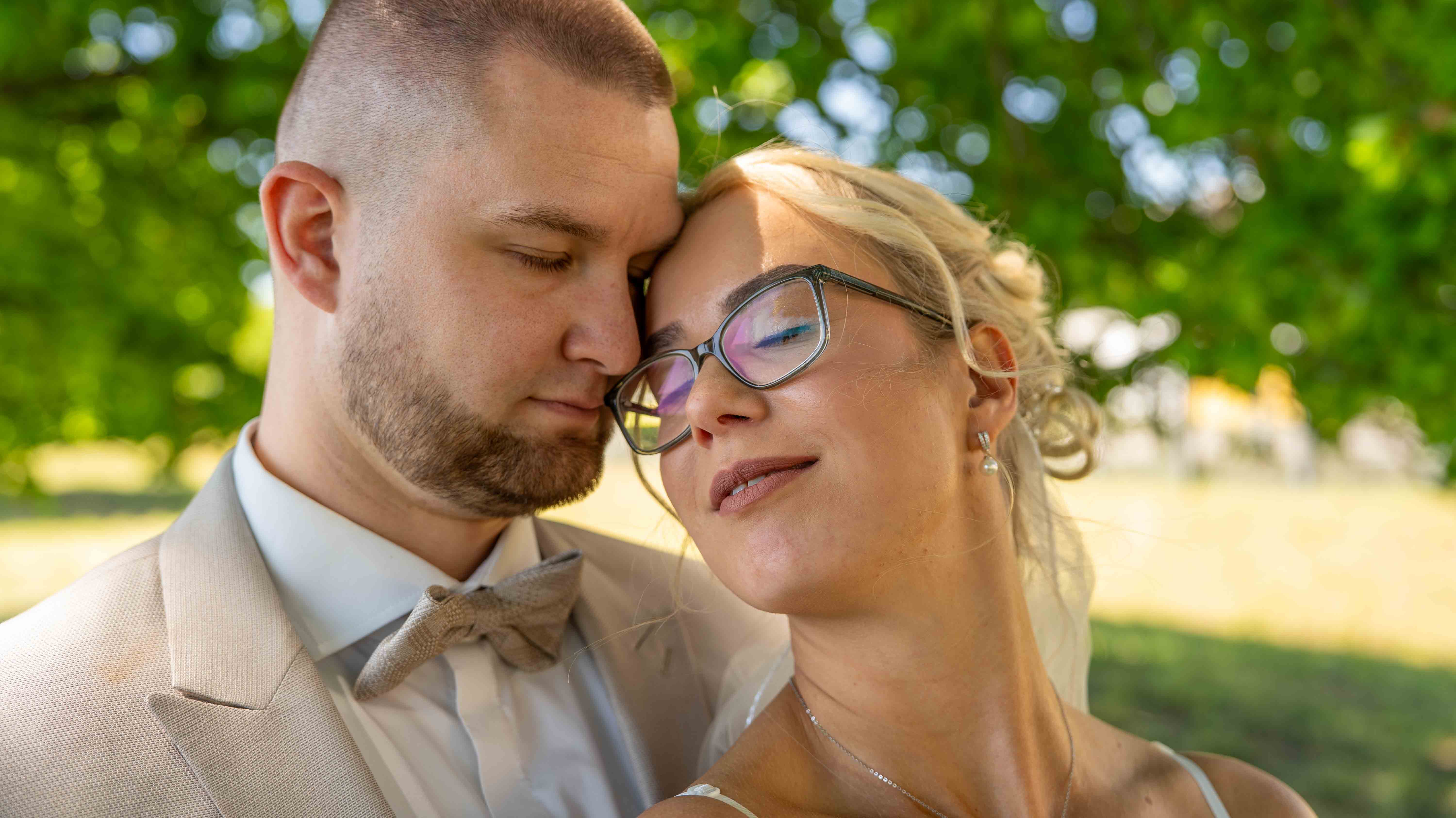 Nahaufnahme der Gesichter von Braut und Bräutigam, die ihre Stirnen sanft aneinanderlehnen und die Augen geschlossen haben.