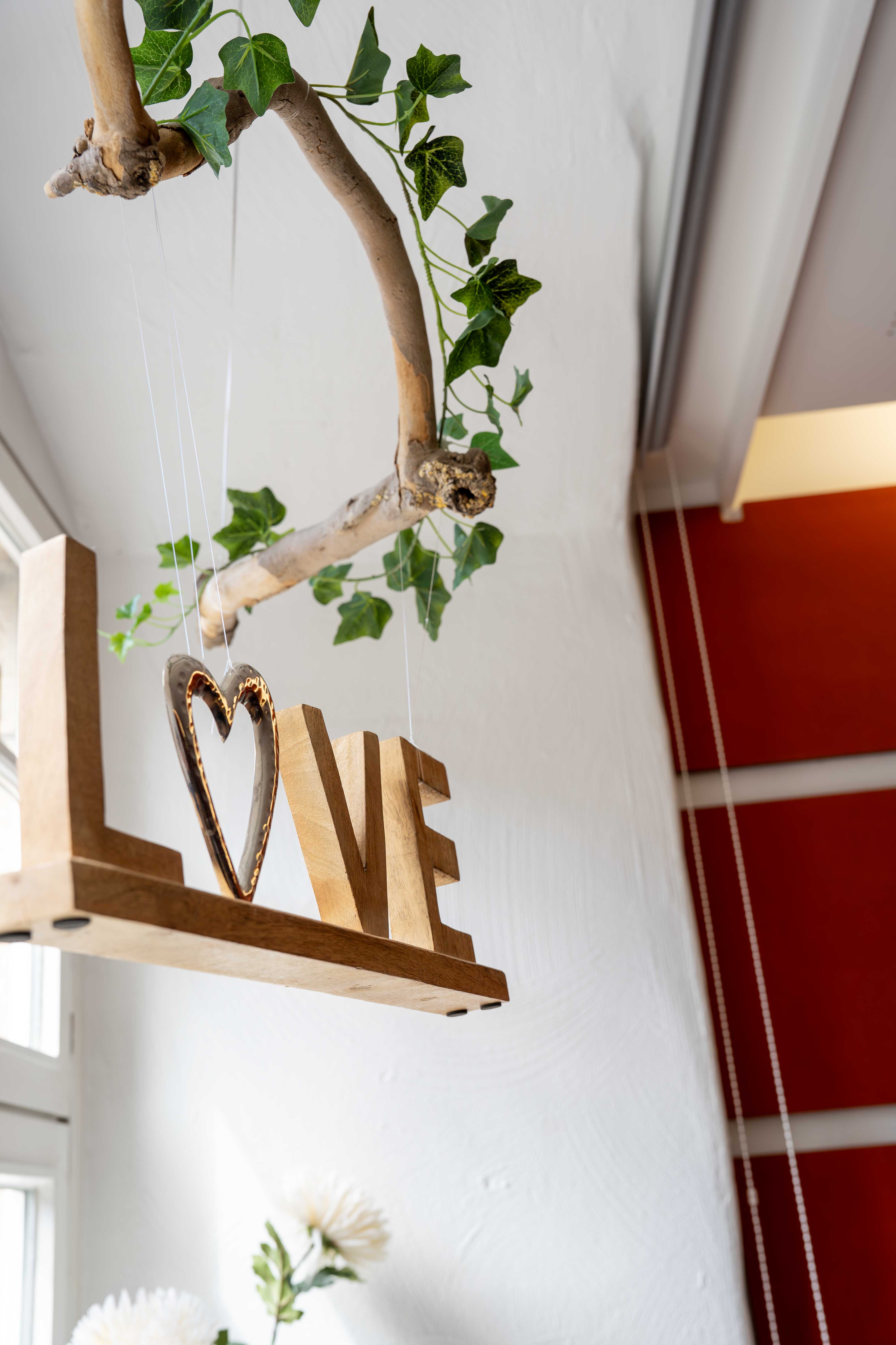 Große, weiße Deko-Buchstaben, die das Wort "LOVE" bilden, hängen von der Decke